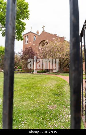 Una chiesa generica vista attraverso i pali di recinzione di acciaio lungo il disegno paesaggistico bello. Fotografia di concetto esterno di giorno Foto Stock