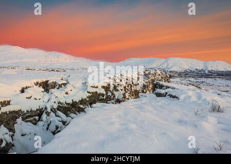 Dawn nel parco nazionale di Thingvellir porta il cielo rosso sulla neve più bianca. Foto Stock