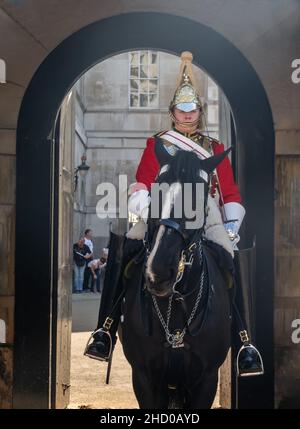 Londra, Inghilterra - 19 Apr, 2019 : una delle Guardia di vita della Regina in uniforme completa con cappotto rosso reale e casco dorato si siede su un cavallo nero al Roy Foto Stock