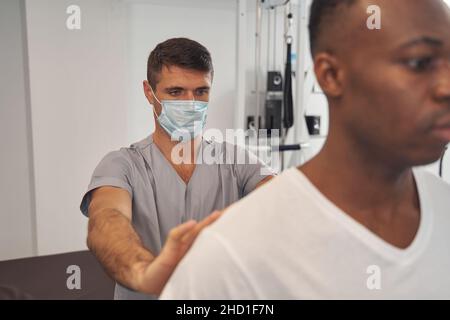 Medico esperto che esamina la colonna vertebrale del giovane uomo Foto Stock