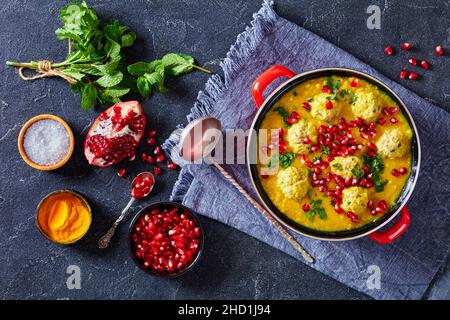 Ash-e Anar, zuppa di Pomegranate di Pea spaccata persiana con polpette di agnello in una pentola rossa su un tavolo di cemento con ingredienti vista orizzontale dall'alto, piatto Foto Stock