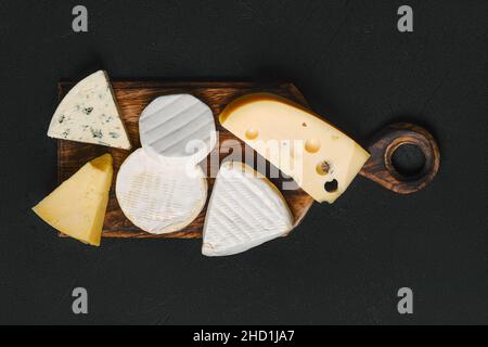 Vista dall'alto del piatto di formaggi. Assortimento di brie, camembert, parmigiano e formaggio gouda su tagliere in legno. Foto Stock