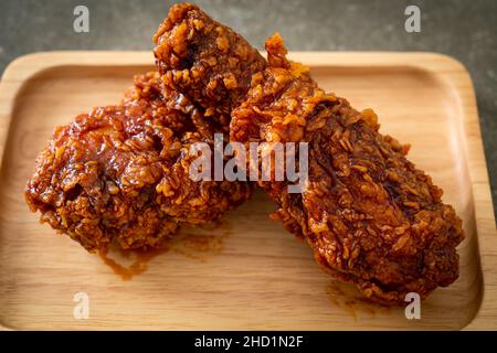 Pollo fritto con salsa piccante coreana su piatto di legno Foto Stock