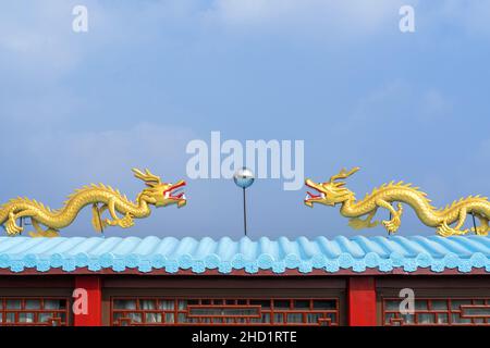 Colpo ad angolo basso di due figurine gialle drago su un tetto blu Foto Stock