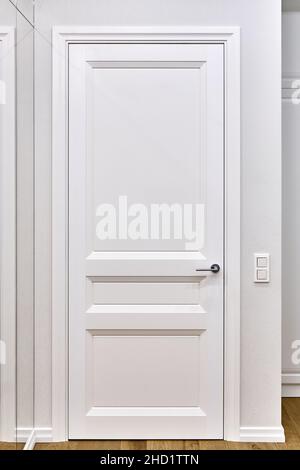 Porta bianca chiusa classica e luci a parete bianca in una spaziosa camera decorata di appartamenti di lusso Foto Stock