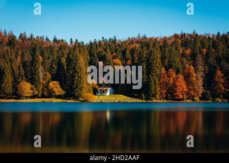 Magnifica vista di una casa solitaria sul lago scenico vicino alla foresta d'autumforest Foto Stock