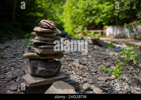 Un cairn, un mucchio artificiale o un mucchio di pietre con un cappello da baseball in cima, si erge sul letto di fiume asciutto al Six-Mile Creek Park, Ithaca, New York. Foto Stock