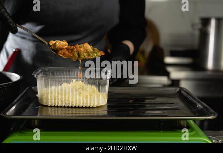 consegna di cibo nel ristorante. Primo piano della mano di uno chef con guanto che pesa una partita di riso su una bilancia elettronica. Piccola impresa. Cibo da asporto. Foto Stock