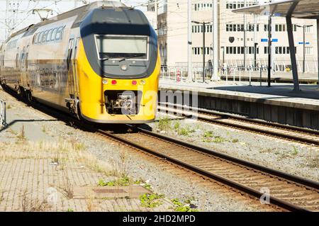 Utrecht, Paesi Bassi - 24 ottobre 2021: Treno giallo e blu sulla ferrovia vicino alla stazione centrale di Utrecht Foto Stock