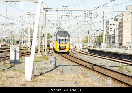 Utrecht, Paesi Bassi - 24 ottobre 2021: Treno giallo e blu sulla ferrovia vicino alla stazione centrale di Utrecht Foto Stock