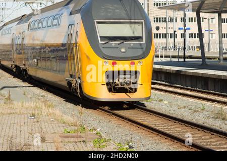 Utrecht, Paesi Bassi - 24 ottobre 2021: Treno giallo e nero sulla ferrovia vicino alla stazione centrale di Utrecht Foto Stock