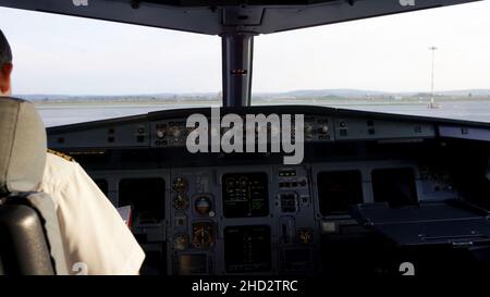 Vista posteriore dei comandi di azionamento pilota del jet aziendale. Capitano nella cabina di pilotaggio dell'aeromobile, preparandosi per la partenza del volo. Concentrandosi sul suo epaulet pilota Foto Stock