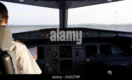 Vista posteriore dei comandi di azionamento pilota del jet aziendale. Capitano nella cabina di pilotaggio dell'aeromobile, preparandosi per la partenza del volo. Concentrandosi sul suo epaulet pilota Foto Stock