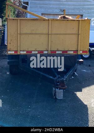 Vista frontale di un dumpster portatile in un vialetto residenziale pieno di rifiuti. Foto Stock