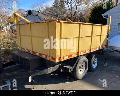 Un dumpster portatile giallo spazzatura su un rimorchio in un vialetto residenziale. Foto Stock