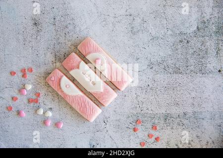 I biscotti di valentine di pan di zenzero si dividono in pezzi con delle spolverette su sfondo grigio. Copia spase, disposizione piatta Foto Stock