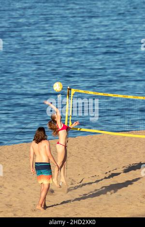 Coppia mista di un uomo e una donna che gioca a pallavolo sulla spiaggia sabbiosa di Pals in Spagna in una giornata di sole Foto Stock