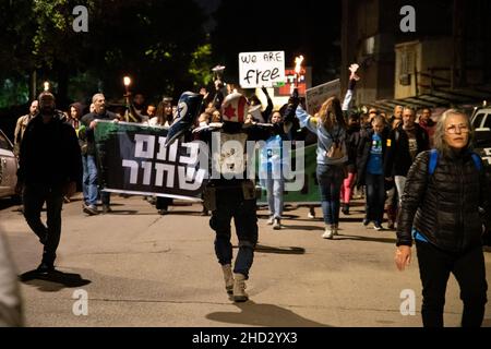 Raanana, Israele. 1st Gennaio 2022. Dimostrazione contro le restrizioni del virus di Corona, i vaccini infantili e la normativa “Green Badge/Pass”. La protesta iniziò nei pressi della residenza del primo ministro Bennett a Raanana, e marciò verso un centro commerciale nella città di Kfar Saba, bloccando le strade principali e gli incroci. La settimana scorsa il governo israeliano ha legiferato sulle nuove restrizioni, impedendo ai cittadini senza passaporto verde di entrare nei negozi dei centri commerciali, oltre ai servizi essenziali, come il cibo e le farmacie. Raánana, Israele. 01th Jan 2022. Credit: Matan Golan/Alamy Live News Foto Stock