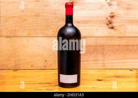 Bottiglia di vino rosso senza segni in colore oro e sfondo in legno Foto Stock