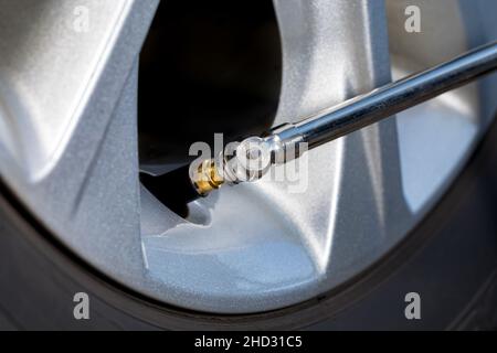 Manometro della pressione dell'aria sullo stelo della valvola del pneumatico della ruota dell'auto. Sicurezza del veicolo, usura degli pneumatici, chilometraggio del carburante e concetto di controllo invernale. Foto Stock