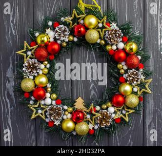 Corona di Natale con palle di Natale e giocattoli appesi su un muro di legno Foto Stock