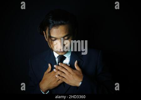 Primo piano di un bell'uomo indiano che indossa un abito di classe su sfondo nero Foto Stock