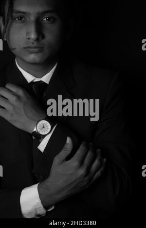 Scatto verticale in scala di grigi di un uomo indiano che indossa un abito e un orologio di classe Foto Stock