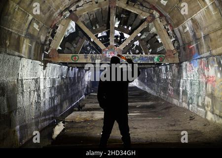 Un uomo che si trova all'interno dell'abbandonato Merriton Tunnel, noto anche come Blue Ghost Tunnel o Grand Trunk Railway Tunnel. Ontario, Canada. Foto Stock