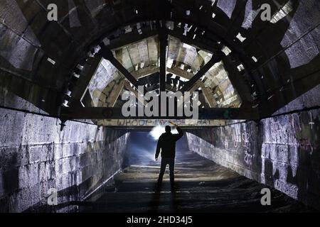 Un uomo che si trova all'interno dell'abbandonato Merriton Tunnel, noto anche come Blue Ghost Tunnel o Grand Trunk Railway Tunnel. Ontario, Canada. Foto Stock