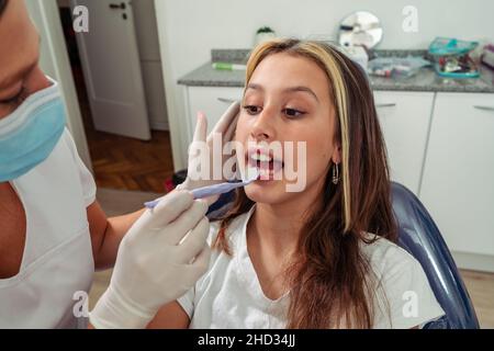 Bellissimo dentista Latina che controlla i denti di una ragazza adolescente. Concetto di salute orale, assicurazione dentale. Foto Stock