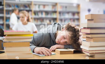 Ragazzo adolescente stanco in biblioteca Foto Stock