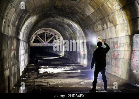 Un uomo che si trova all'interno dell'abbandonato Merriton Tunnel, noto anche come Blue Ghost Tunnel o Grand Trunk Railway Tunnel. Ontario, Canada. Foto Stock