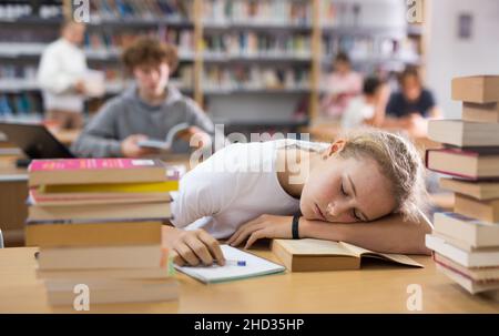 Ragazza adolescente stanca in biblioteca Foto Stock