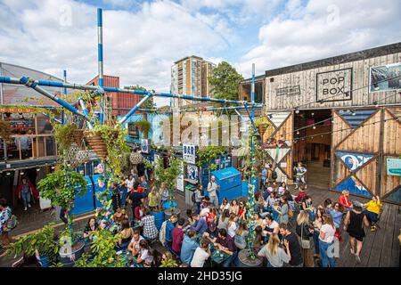 Le persone godono di un drink a Brixton pop, pop up contenitore bar e ristoranti a Brixton, London, Regno Unito Foto Stock