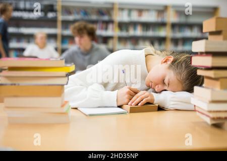 Ragazza adolescente stanca in biblioteca Foto Stock