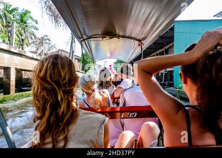 Seduto sul retro con 2 donne di fronte e più persone di fronte a loro nel tour galleggiante mercato in barca. Foto Stock