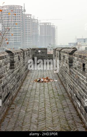 Porzione di un'antica parete sullo sfondo di edifici moderni in una giornata di nebbia. Jiashan, Cina Foto Stock