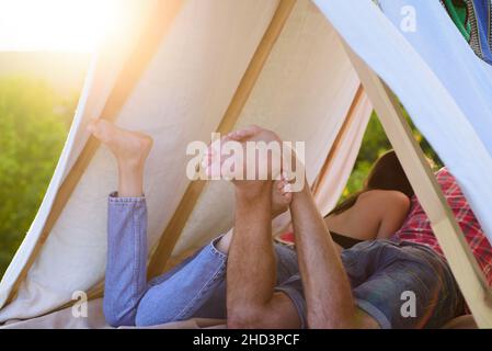Coppia escursionisti campeggio sulla natura. Vista posteriore gambe di coppia in tenda. Migliore amico. Concentrati sui piedi. Amanti romantici in vacanza campeggio in tenda. Coppie Foto Stock