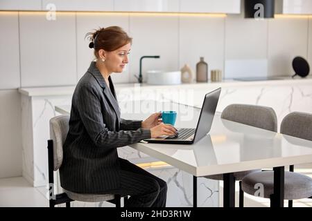 Live streaming di classi virtuali da donna in tuta aziendale con notebook. Foto Stock