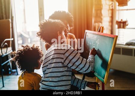 I bambini felici imparano la matematica con la madre, insegnante nel paese. Concetto di felicità per l'educazione familiare Foto Stock