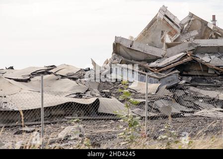 Calcestruzzo industriale distrutto da sciopero. Scenario di disastro pieno di detriti, polvere e edifici schiacciati. Foto Stock