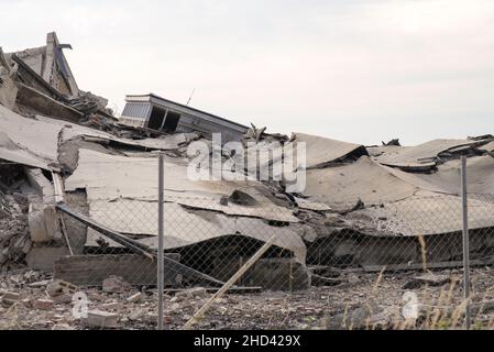 Calcestruzzo industriale distrutto da sciopero. Scenario di disastro pieno di detriti, polvere e edifici schiacciati. Foto Stock