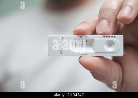 Primo piano di una mano che contiene un test antigene negativo per COVID-19. Foto Stock