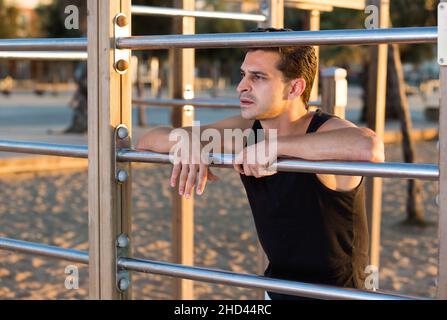 Uomo sportivo vicino a barre da parete esterne Foto Stock