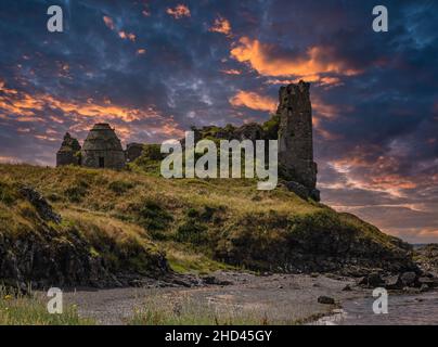 Dunure Rugged difesa del mare, le sue antiche rovine del castello si sgretolano sulla riva sottostante al tramonto con un cielo drammatico e pesante al tramonto. Foto Stock