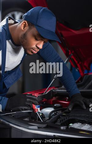 caposquadra afroamericana con cacciavite che fa la diagnostica del motore dell'automobile Foto Stock