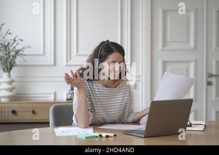 Giovane eccitata allenatore femminile in cuffia con microfono conduce consultazioni private online Foto Stock