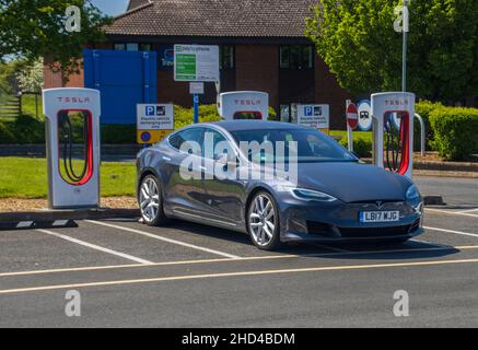 Grantham, Regno Unito - Maggio 30th 2021: Tesla modello 3 in un alloggiamento per super caricabatterie nell'area di servizio autostradale di Gonerby Moor. Foto di alta qualità Foto Stock