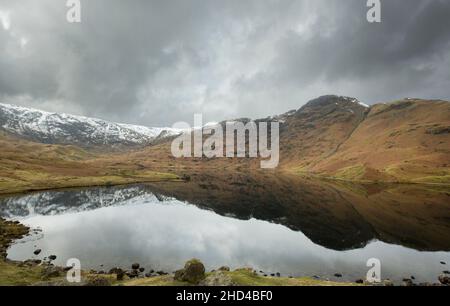 Easedale Tarn sopra Grasmere in inverno con le campane coperte di neve riflesse nell'acqua still, il Parco Nazionale del Distretto del Lago, Cumbria, Inghilterra Foto Stock
