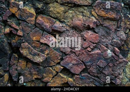Foto in pietra crackizzata e testurizzata di colore giallo e magenta. Texture e design della roccia senza cuciture e ruvidi. Foto Stock